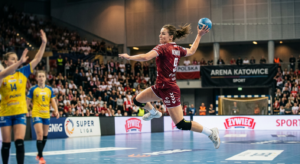 A professional, high-quality editorial photograph capturing a focused handball player in mid-air dur