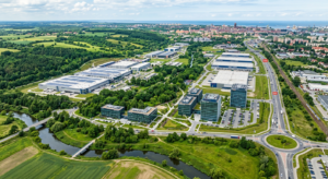 A professional, high-angle aerial view of a modern Polish industrial park integrated with a lush gre