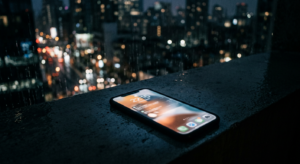 A conceptual, editorial photograph of a blurred, glowing smartphone screen resting on a dark, minima