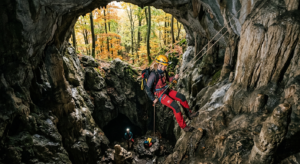 A cinematic, high-angle editorial photograph of a professional explorer descending into a rugged lim